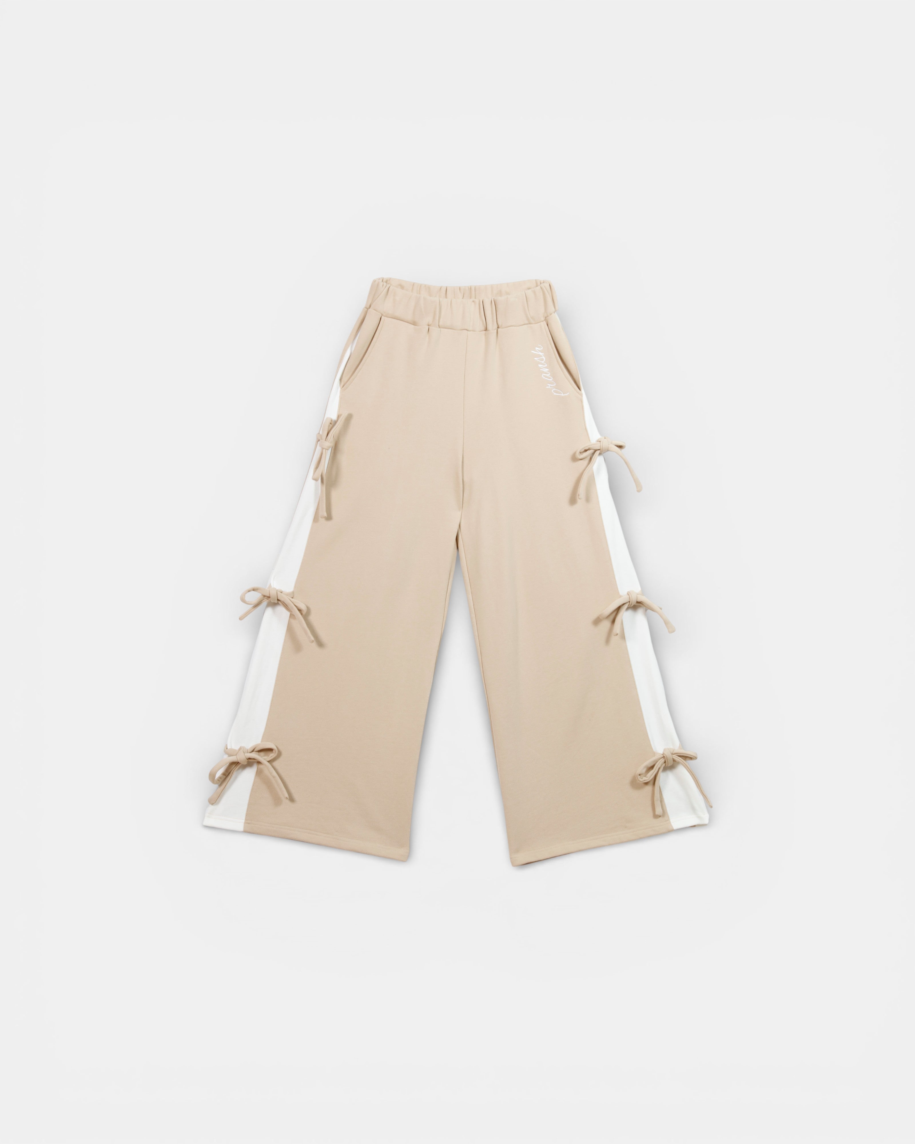 Beige pants with tie details, and side panels on a white background